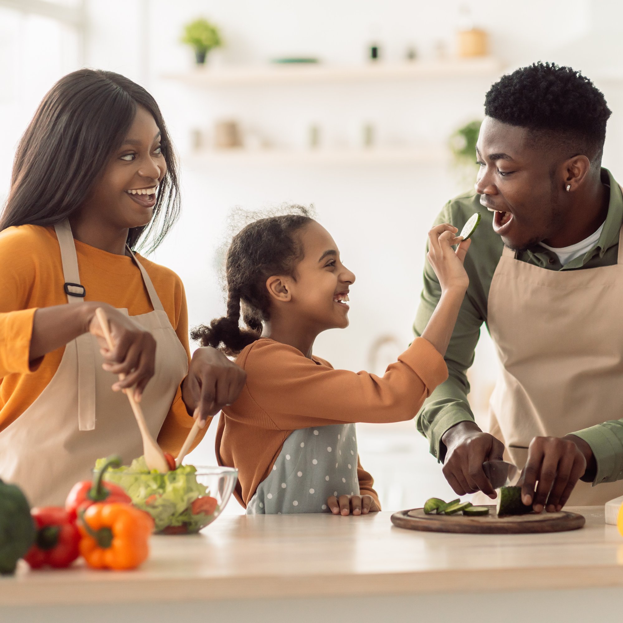 black-family-cooking-daughter-feeding-father-whil-2022-12-16-09-24-55-utc-1